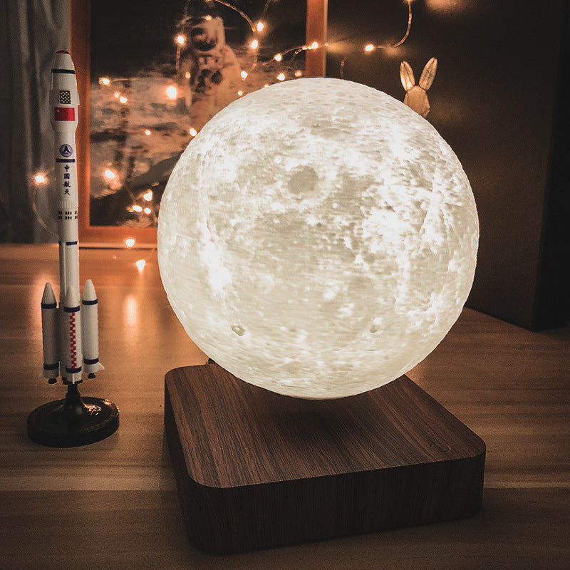 moon lamp levitating over a wooden base, next to a toy rocket